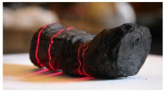 Herculaneum scroll with red laser lines being scanned at Institut de France by Brent Seales and his team.